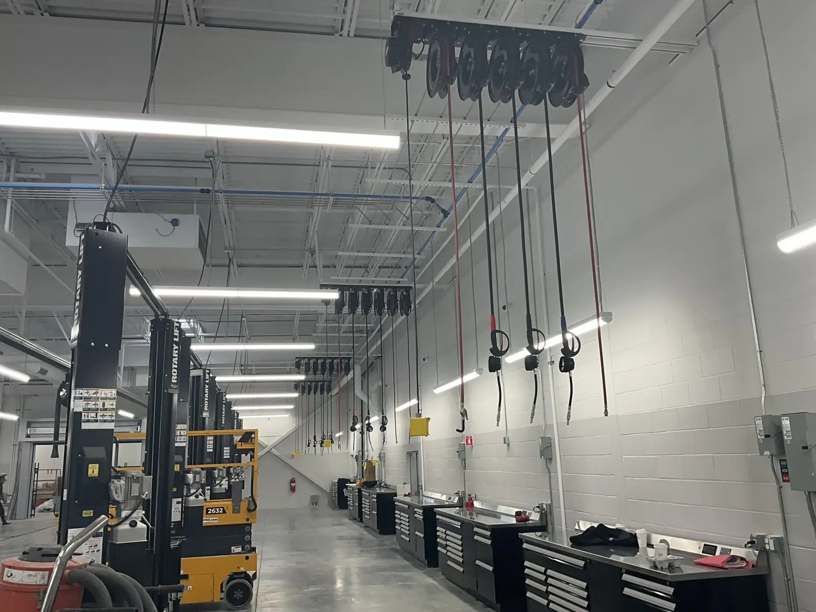 Completed dealership service bays with lifts, storage, and overhead utilities