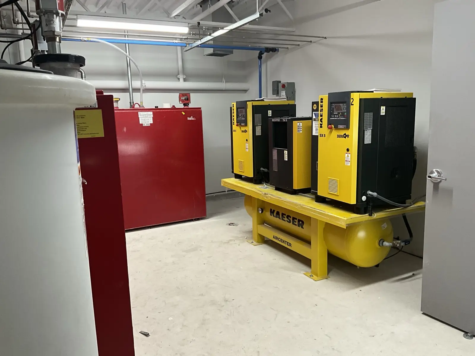 Kaeser compressed-air equipment installed beside bulk fluid storage